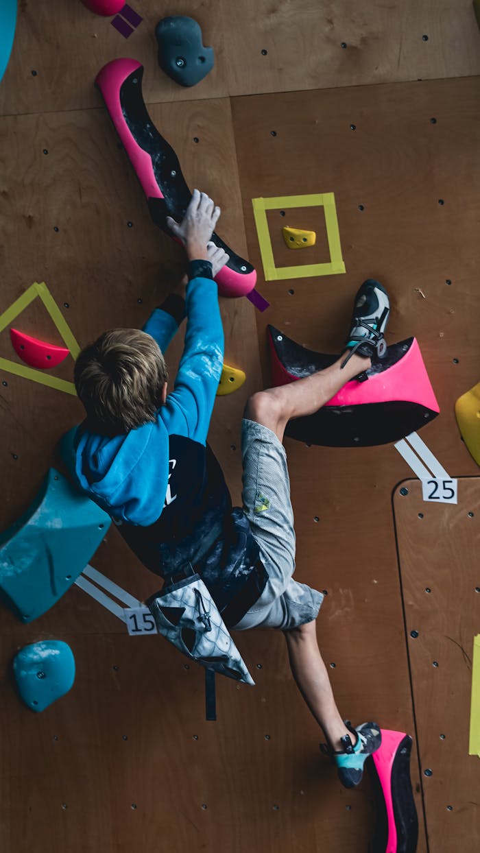 Young boy skillfully climbing a colorful indoor rock wall, showcasing agility and focus.